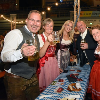 Das Foto zeigt lachende Männer und Frauen in bayerischer Tracht und mit Bierkrügen in der Hand.
