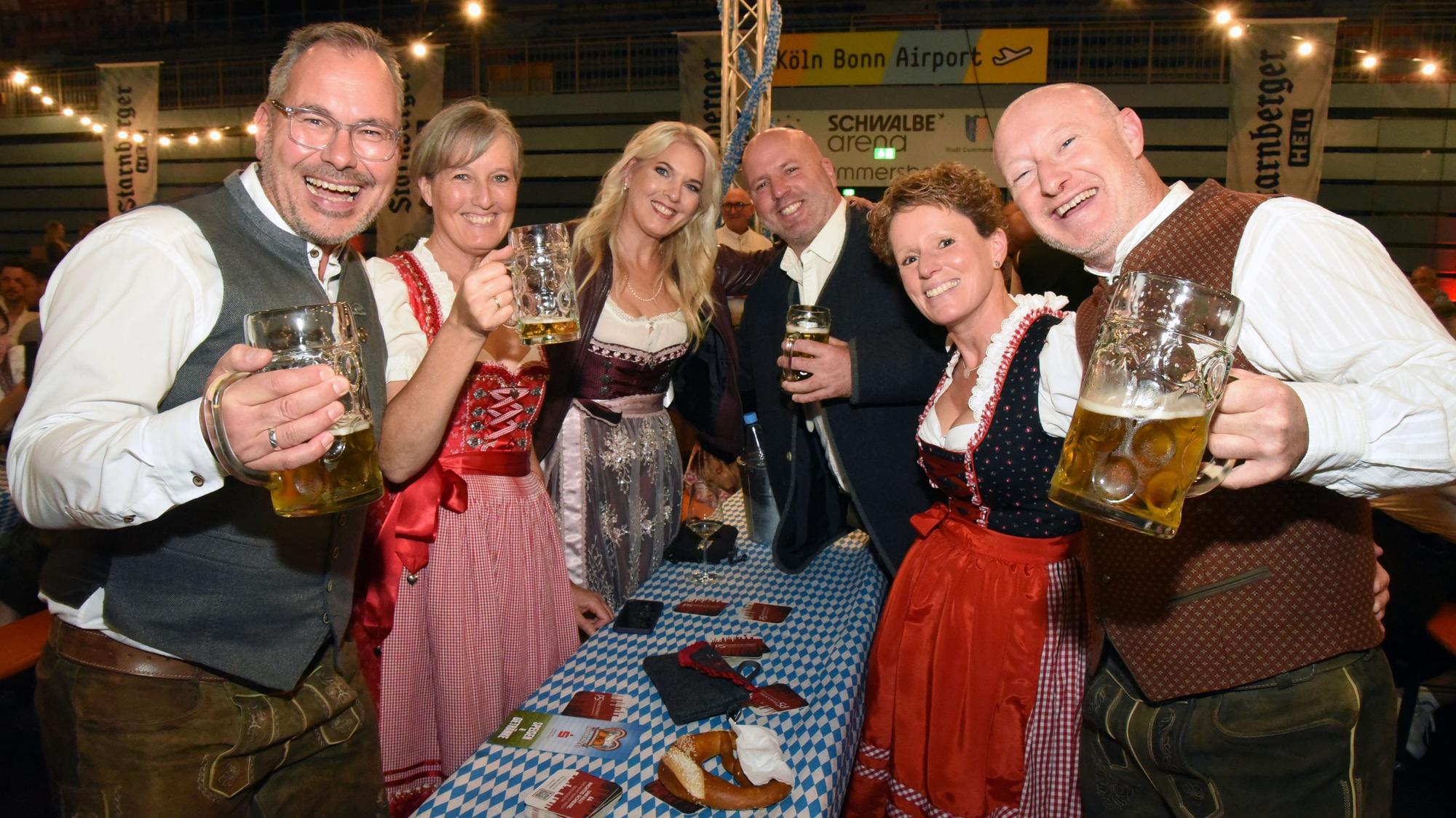 Das Foto zeigt lachende Männer und Frauen in bayerischer Tracht und mit Bierkrügen in der Hand.