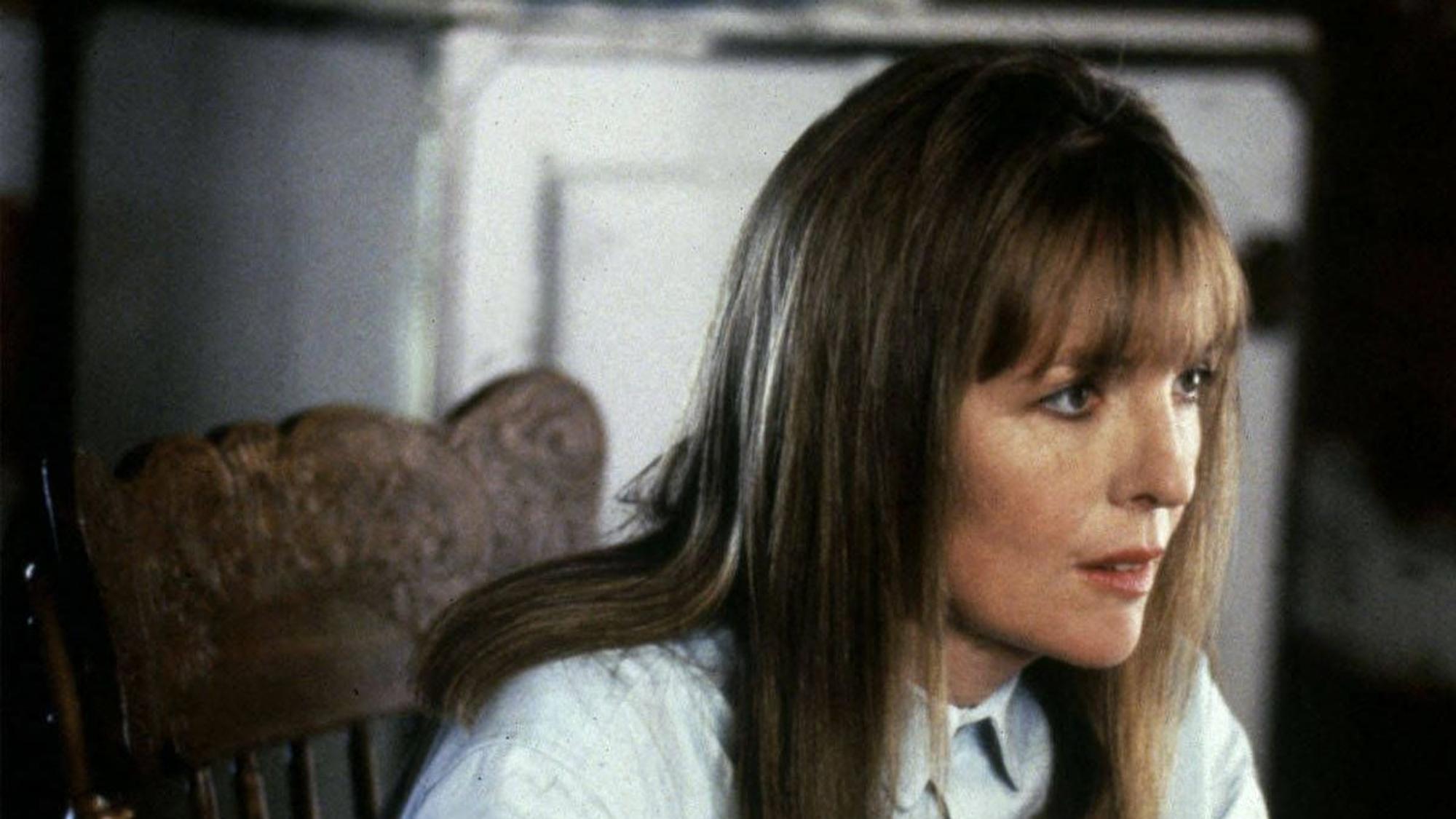 Diane Keaton schält in hellblauem Hemd einen Apfel