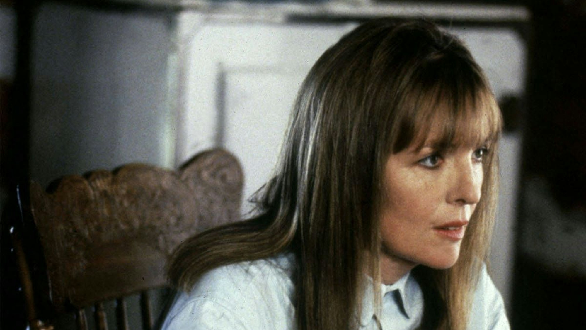 Diane Keaton schält in hellblauem Hemd einen Apfel