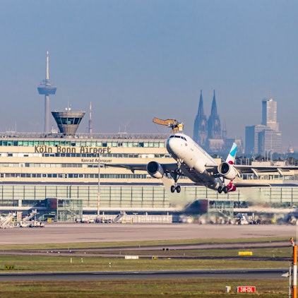 Am Flughafen Köln/Bonn hebt eine Eurowings-Maschine ab. Im Hintergrund sind Dom und Colonius zu sehen.