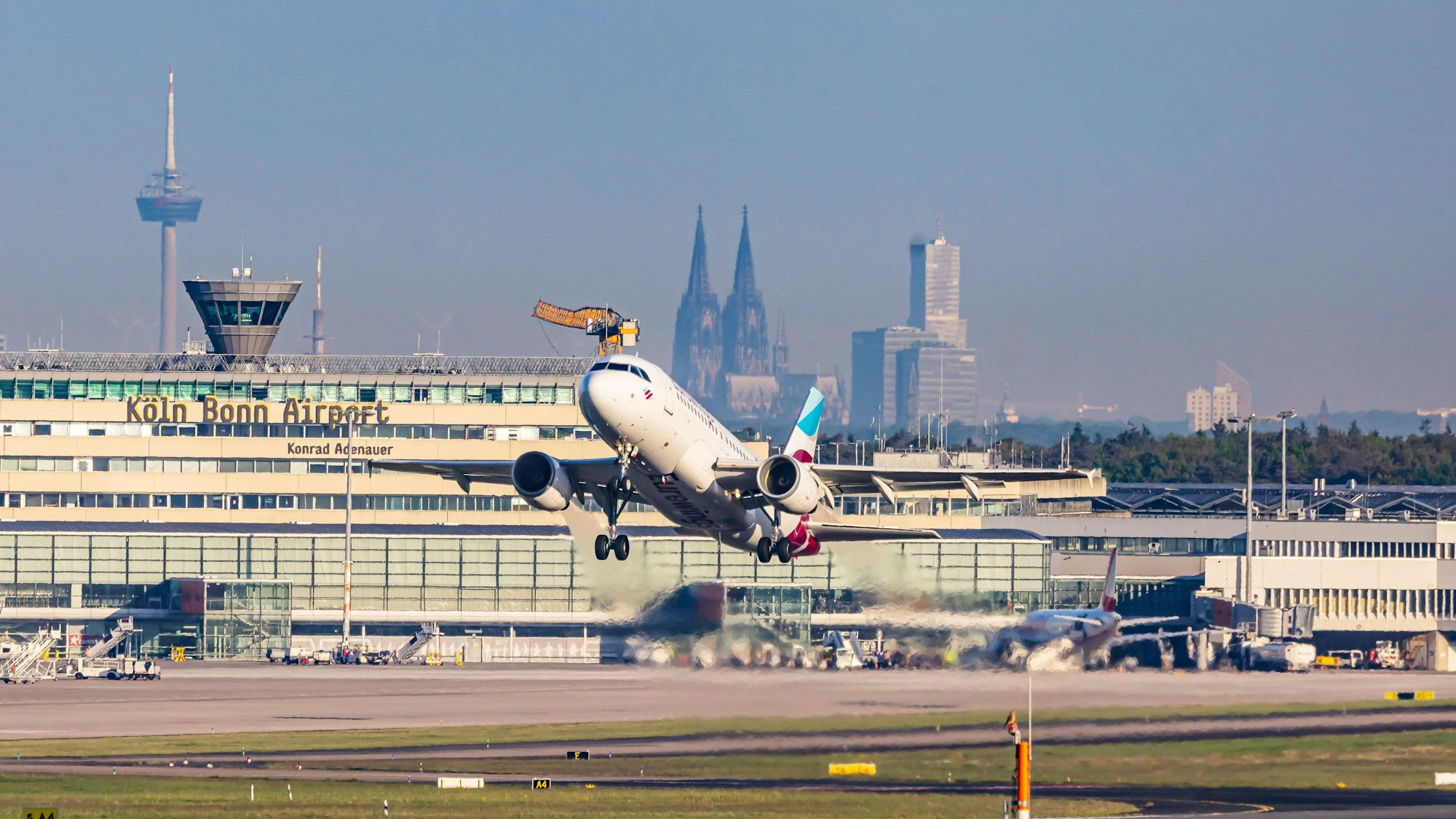Am Flughafen Köln/Bonn hebt eine Eurowings-Maschine ab. Im Hintergrund sind Dom und Colonius zu sehen.