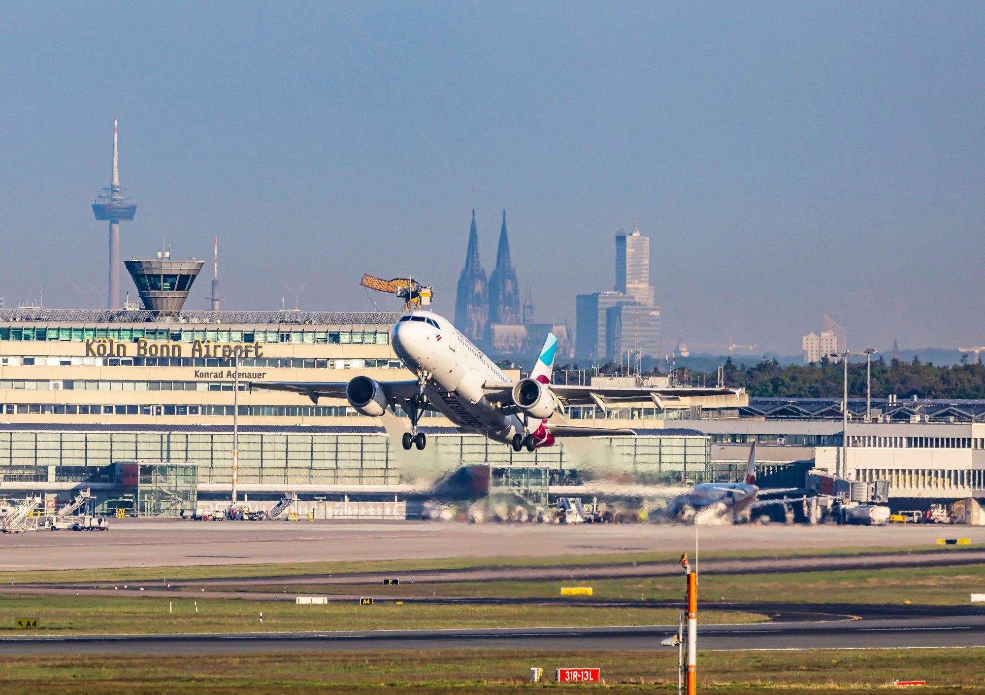 Am Flughafen Köln/Bonn hebt eine Eurowings-Maschine ab. Im Hintergrund sind Dom und Colonius zu sehen.