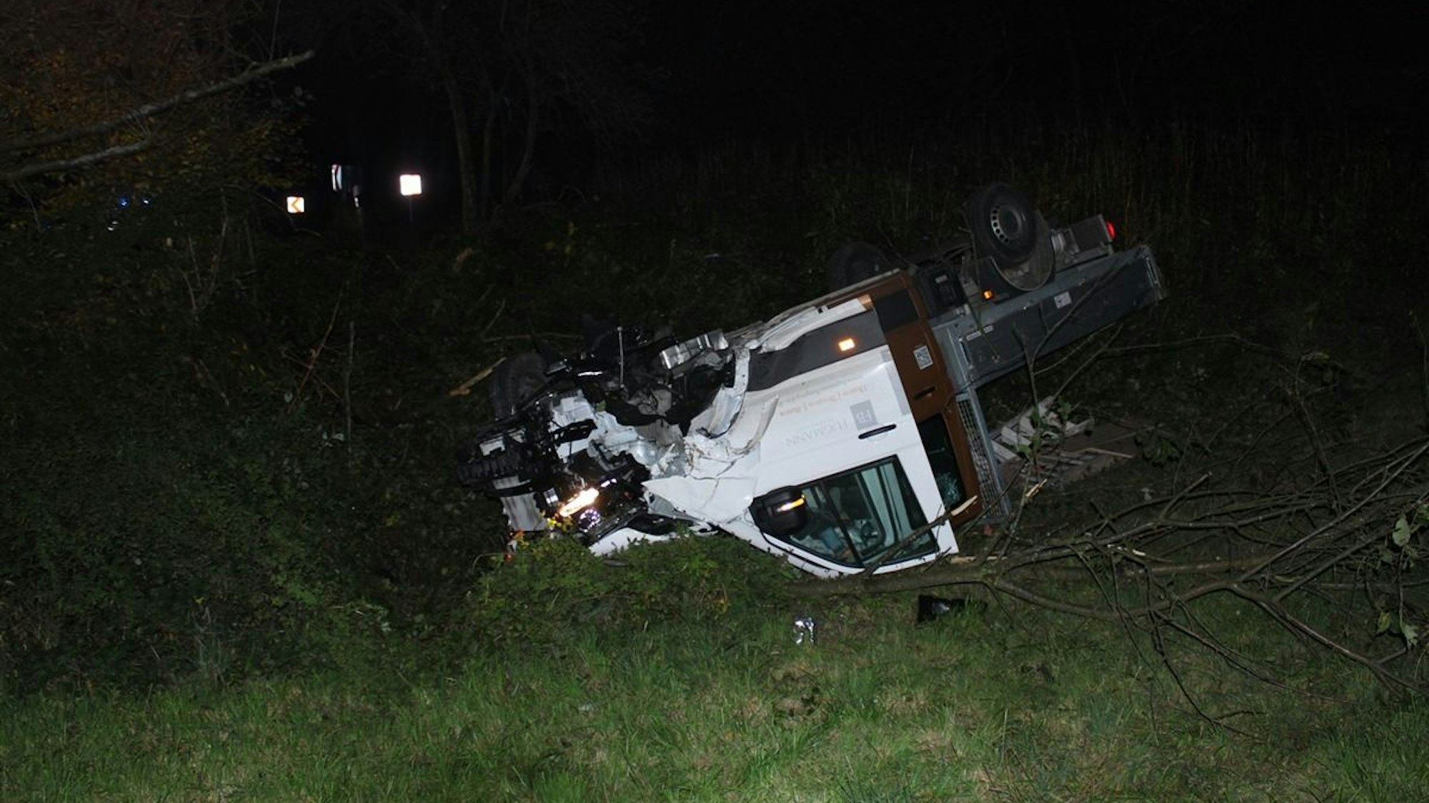 Ein umgekippter Lkw liegt nach einem Unfall an einer Böschung.