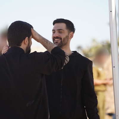 Die beiden Männer stehen sich gegenüber und schauen sich lächelnd an.