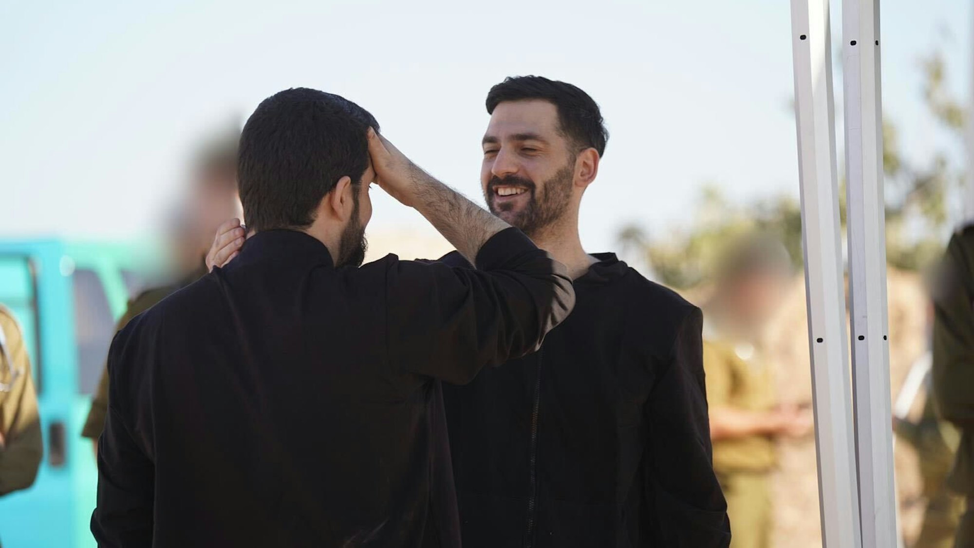 Die beiden Männer stehen sich gegenüber und schauen sich lächelnd an.