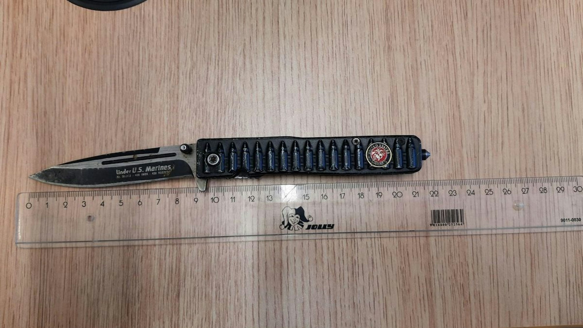 Ein beschlagnahmtes Springmesser und ein Reizstoffsprühgerät liegen auf einem Tisch.