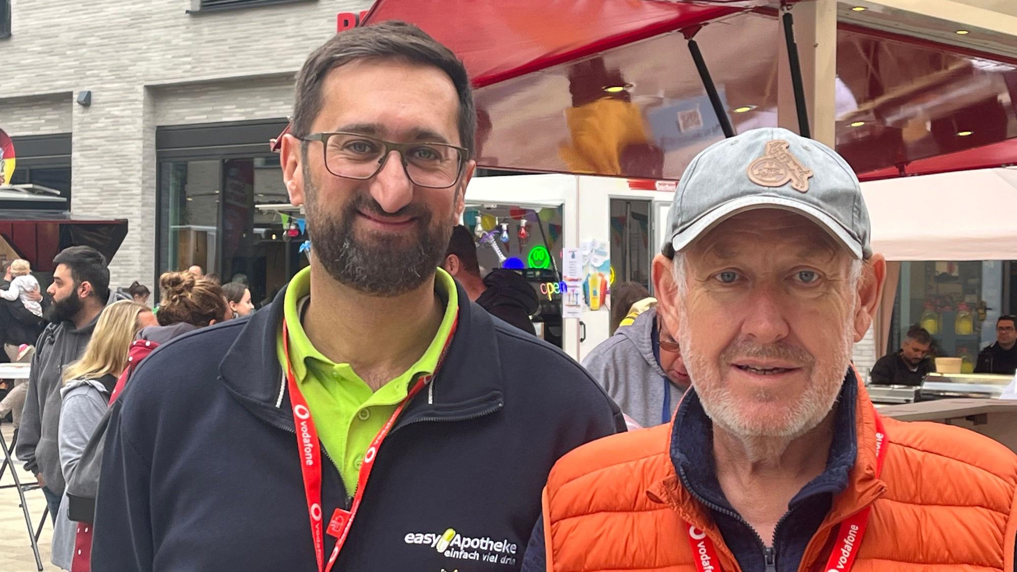 Zwei Männer stehen in der Porzer Innenstadt an einem Stand.