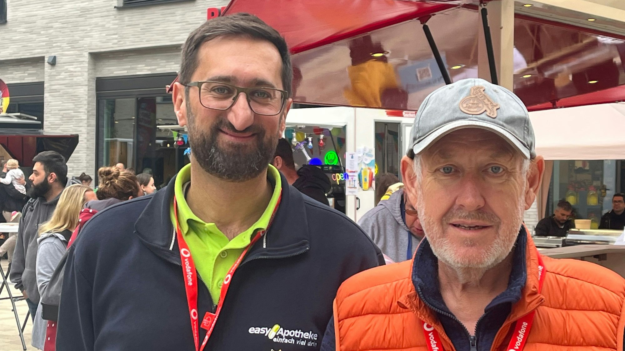 Zwei Männer stehen in der Porzer Innenstadt an einem Stand.