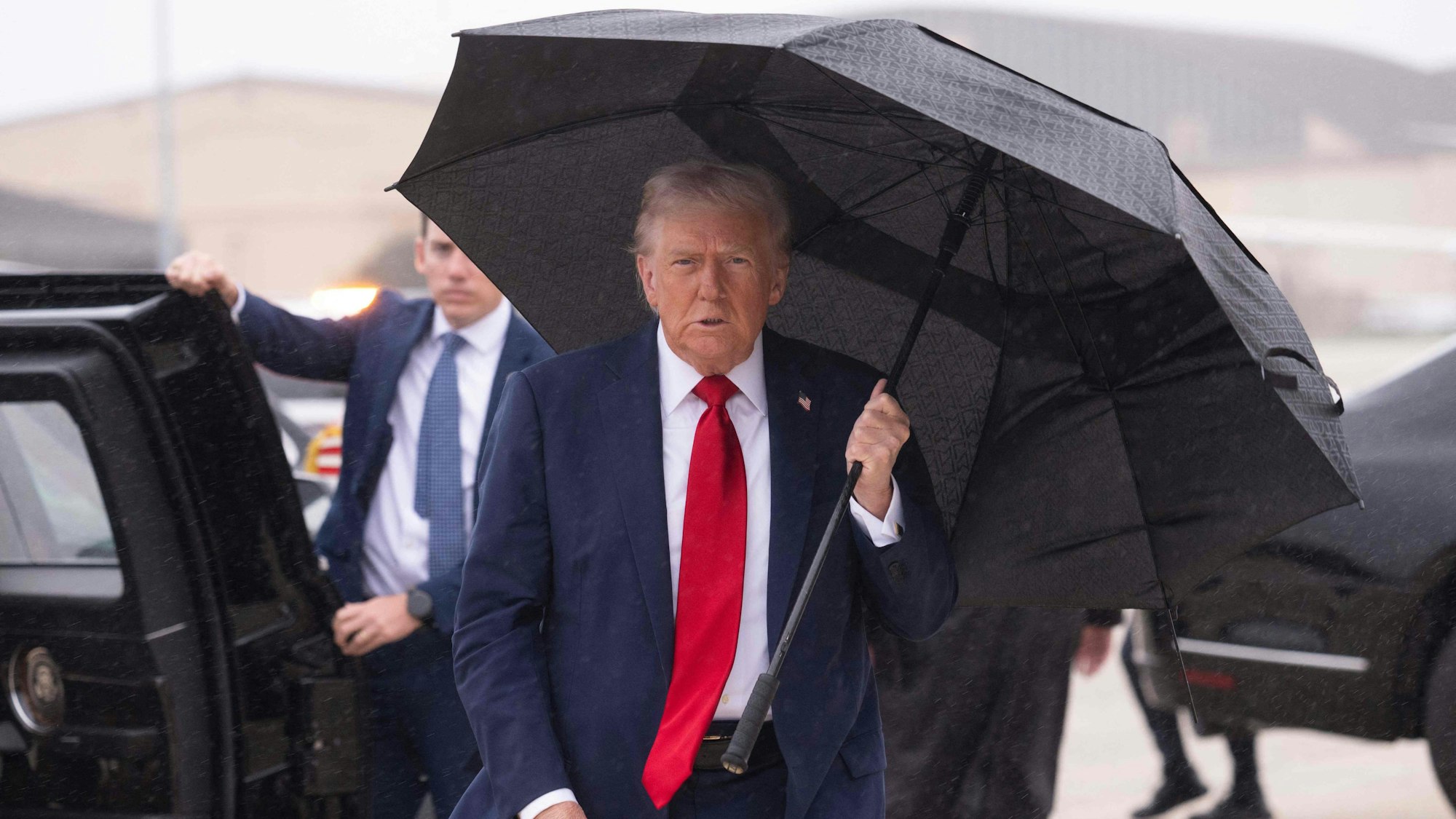 Donald Trump mit einem Regenschirmen.