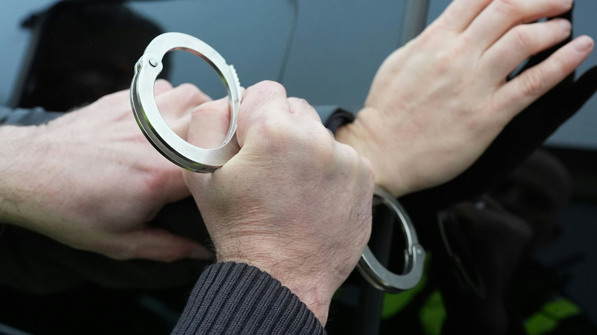 Ein Polizist legt einem Mann Handschellen an.