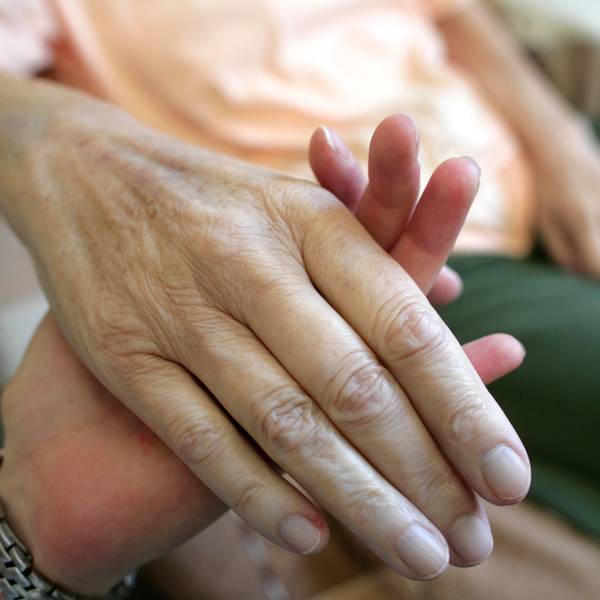Die Hand einer kranken Frau wird gehalten.