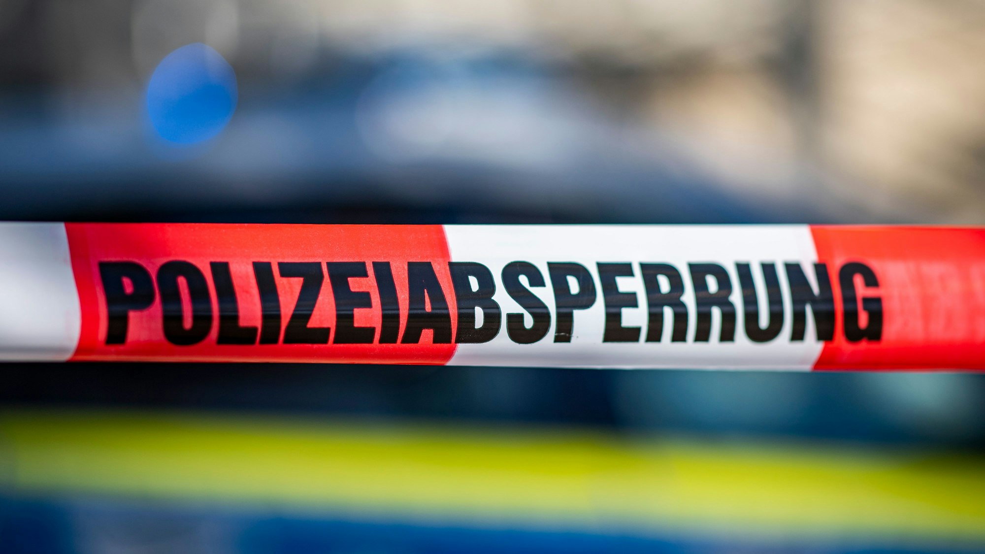 ILLUSTRATION - 28.09.2021, Nordrhein-Westfalen, Gütersloh: Ein Absperrband mit der Aufschrift «Polizeiabsperrung» ist vor einem Polizeiwagen aufgespannt. (zu dpa: «Bomben beim Baggern in Unterfranken gefunden») Foto: David Inderlied/dpa +++ dpa-Bildfunk +++