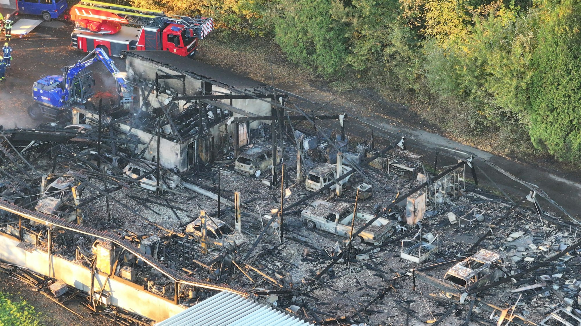 Blick auf die durch das Feuer zerstörte Halle (Luftaufnahme mit einer Drohne). Die Autos sind völlig zerstört.