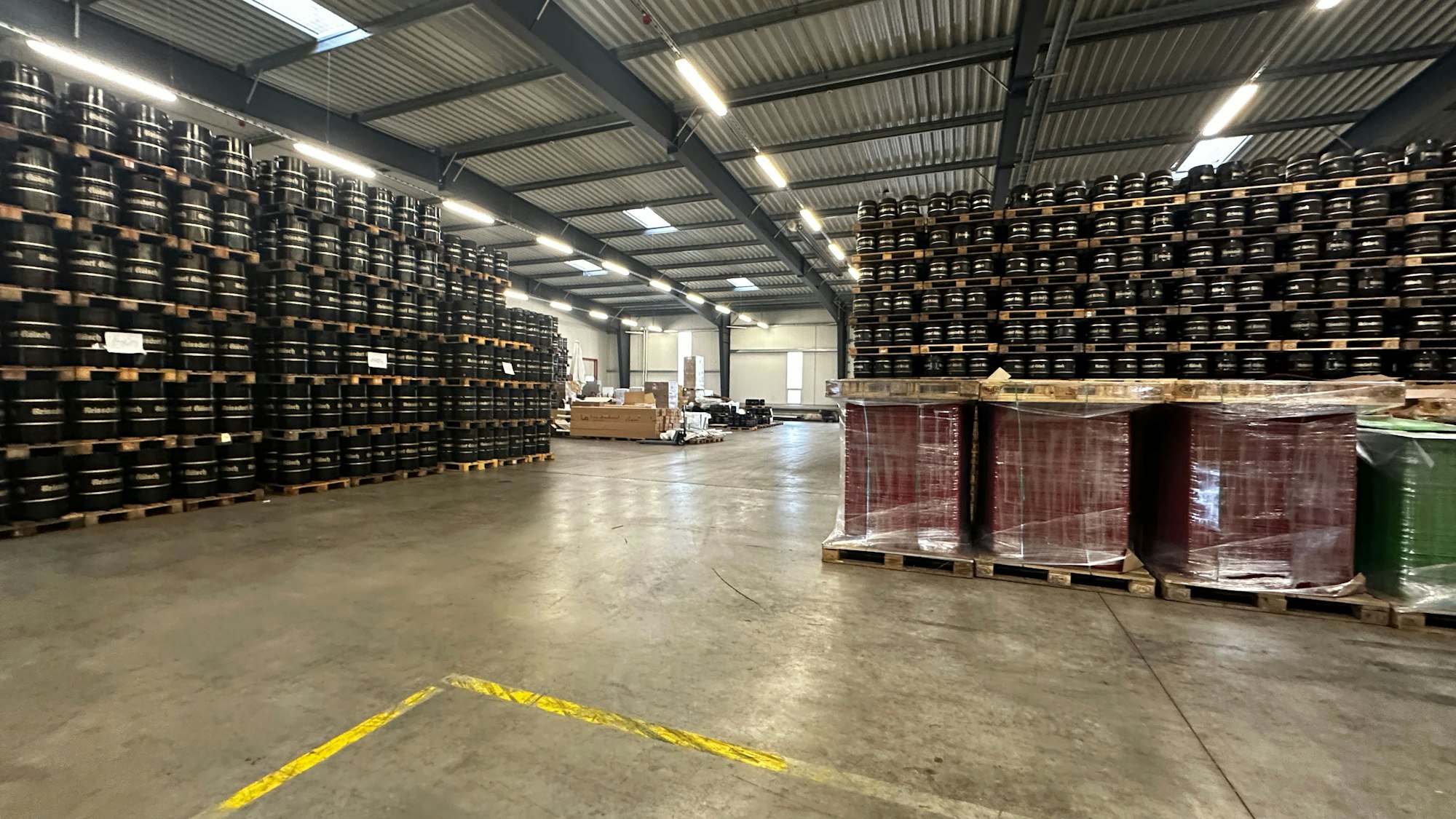 In einer riesigen Lagerhalle stapeln sich Kölschfässer auf Paletten.