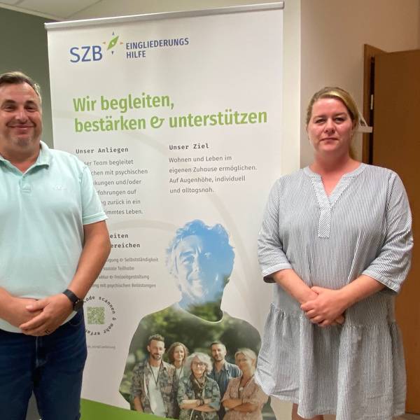 Thomas Sohr und Jessica Breitbarth stehen vor einem Banner, auf dem die SZB für ihre Angebote wirbt.