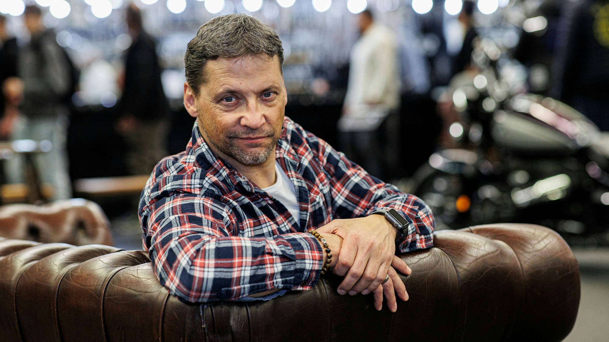 Patrick Bach sitzt auf einer Couch.