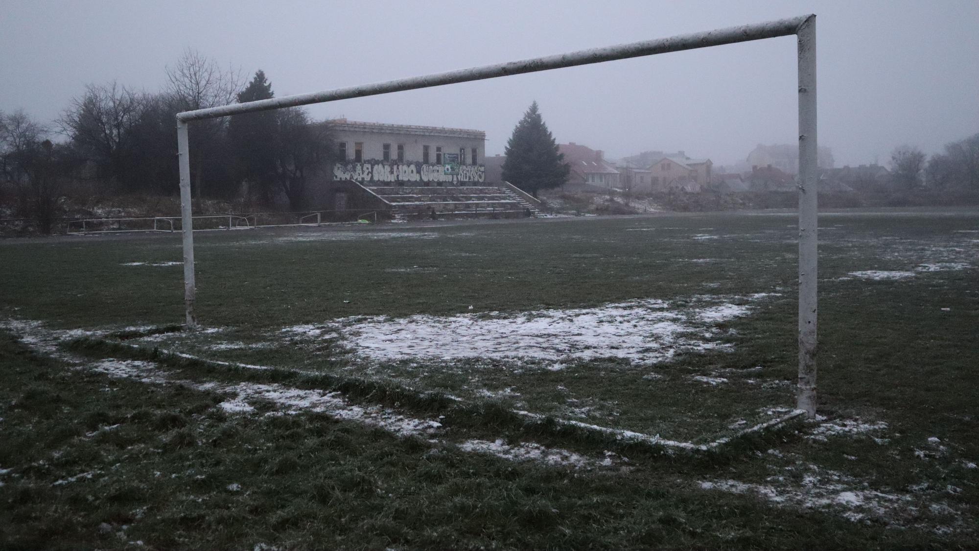 Ein verlassenes Fußballstadion. Im Vordergrund ein Tor ohne Netz.