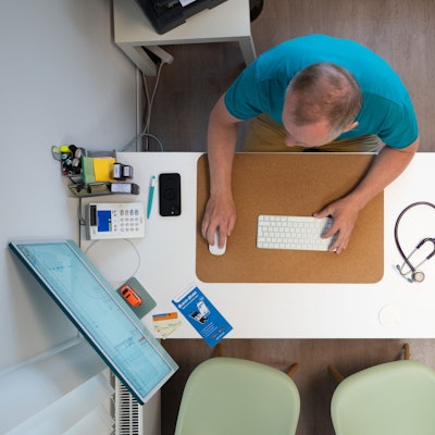 ILLUSTRATION - 27.05.2025, Sachsen, Dresden: Ein Hausarzt sitzt in einem Sprechzimmer seiner Hausarztpraxis an einem Schreibtisch neben einem Stethoskop und arbeitet am Computer. (zu dpa: «Wie startet der Vollbetrieb der E-Patientenakten?») Foto: Sebastian Kahnert/dpa +++ dpa-Bildfunk +++