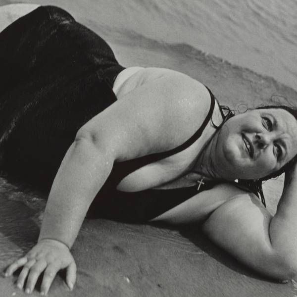 Eine Frau liegt am Strand und schaut in den Himmel.