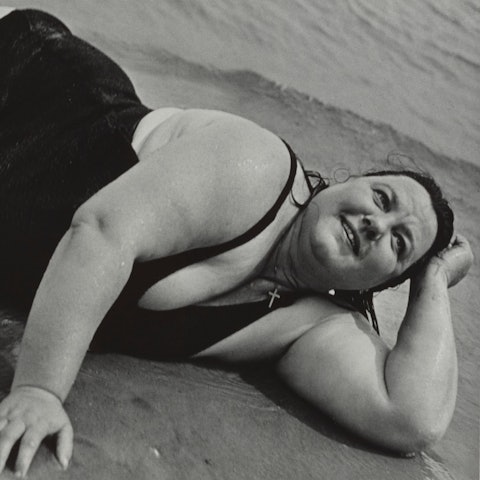 Eine Frau liegt am Strand und schaut in den Himmel.