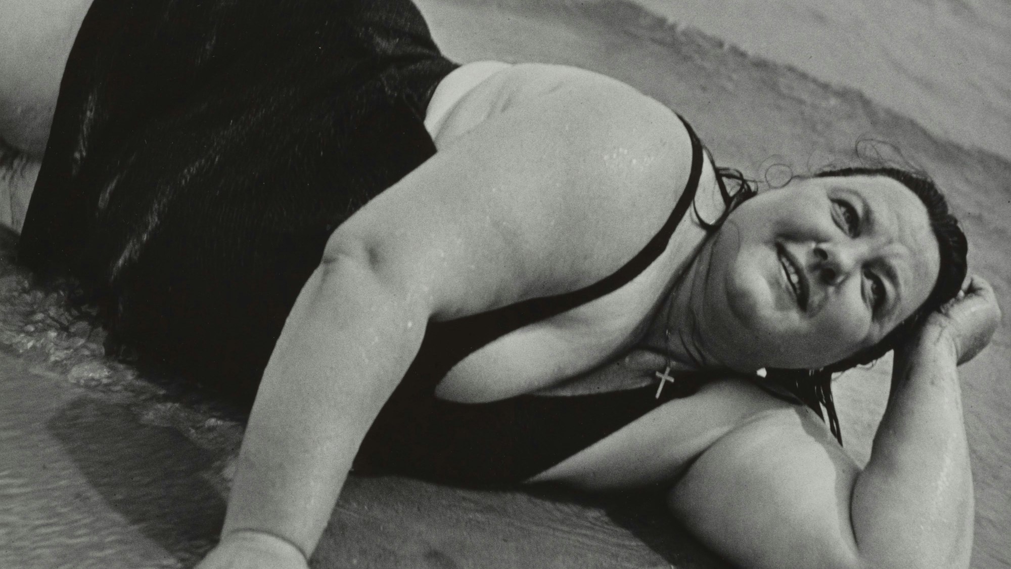 Eine Frau liegt am Strand und schaut in den Himmel.