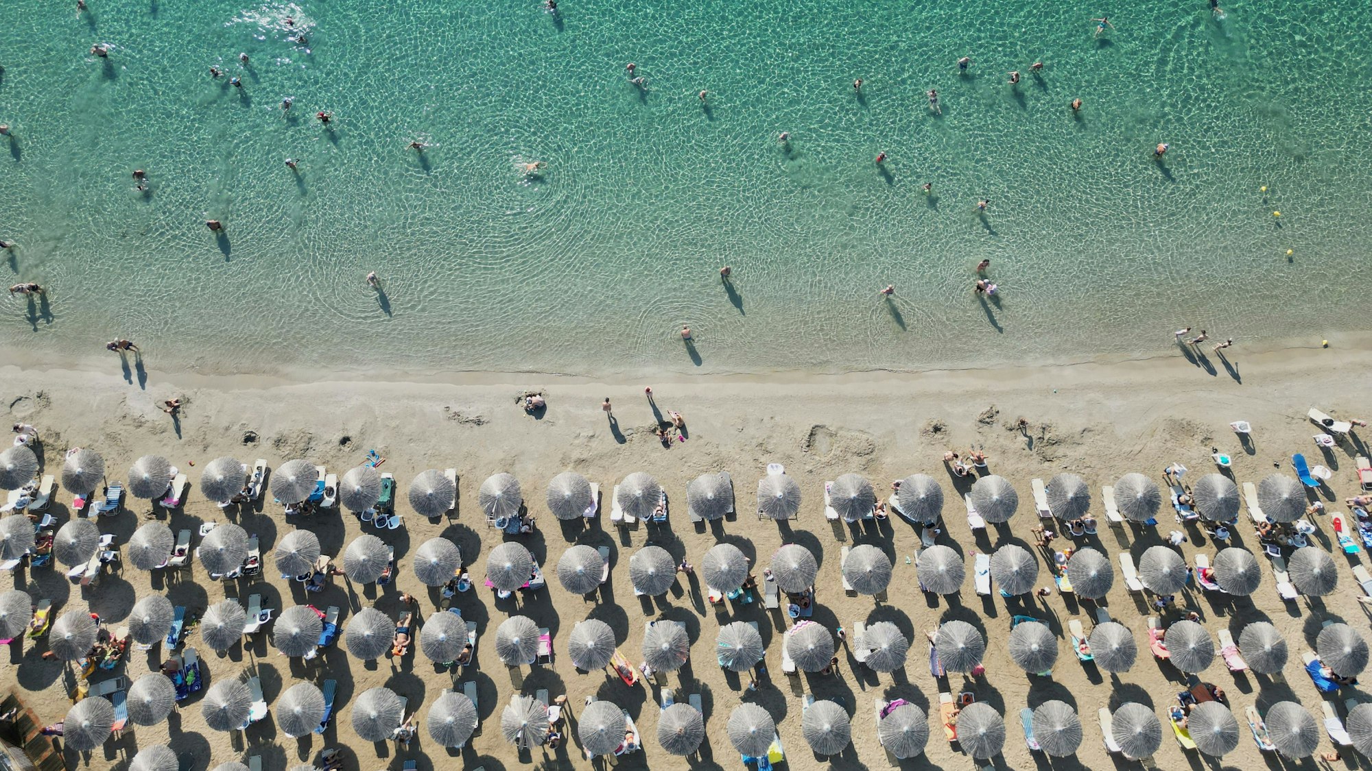 Menschen genießen das Meer an einem Strand in Griechenland.