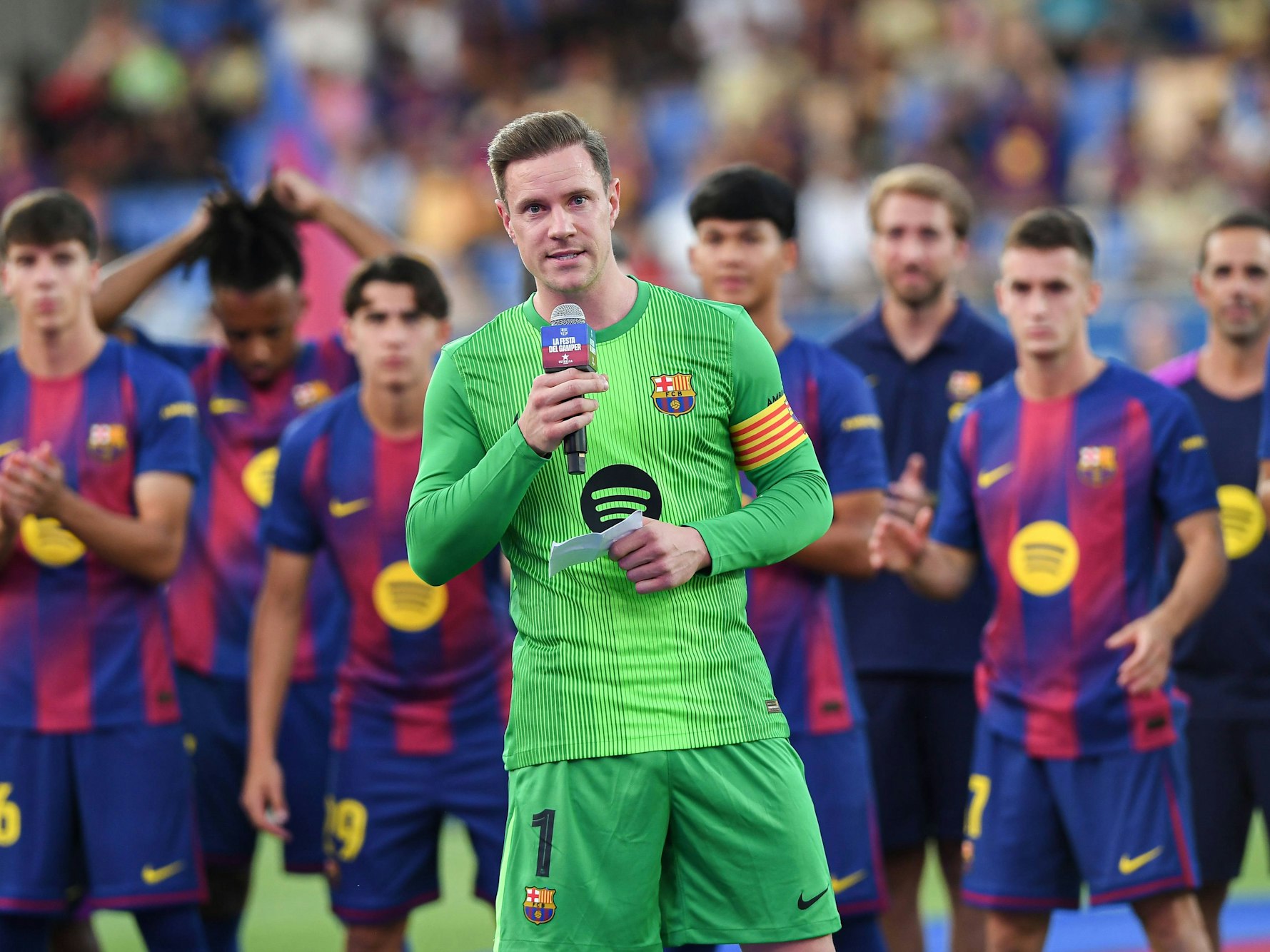 Marc-André ter Stegen spricht in ein Mikro, seine Teamkollegen in Barcelona stehen hinter ihm.