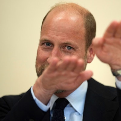 Prinz William lächelt und gestikuliert mit verschwommenen Händen im Vordergrund