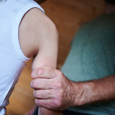 Das Symbolbild zeigt in einer gestellten Szene, wie ein Mann ein Kind am Arm festhält. Zu sehen sind nur Körperausschnitte.