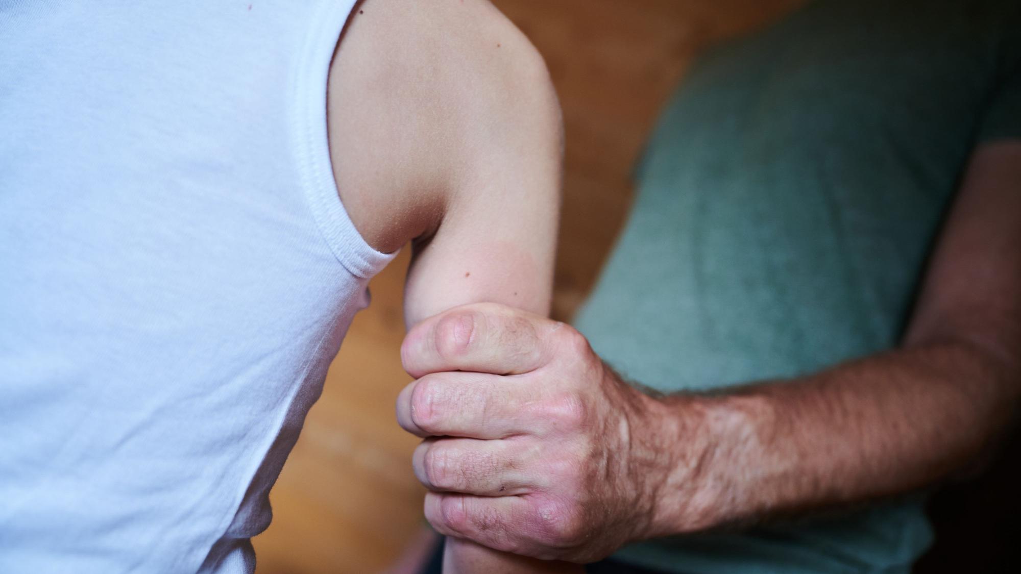 Das Symbolbild zeigt in einer gestellten Szene, wie ein Mann ein Kind am Arm festhält. Zu sehen sind nur Körperausschnitte.