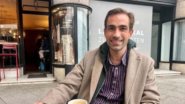 Ein Mann sitzt vor einer Tasse Kaffee.