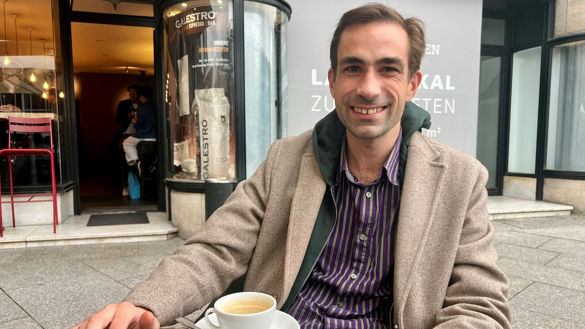 Ein Mann sitzt vor einer Tasse Kaffee.