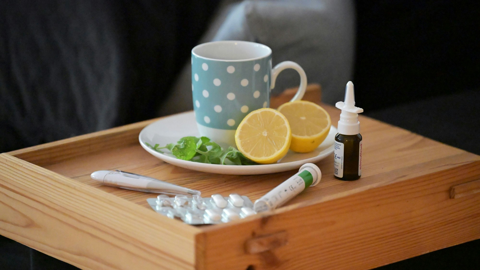 Die Zahl der Corona-Erkrankungen steigt wieder (Symbolbild mit Teetasse, Tabletten und Nasenspray)