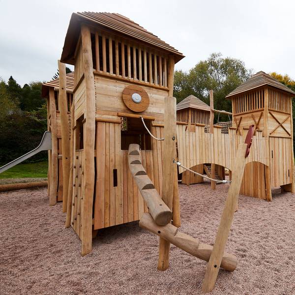 Auf einem Spielplatz steht eine Burg aus Holz.
