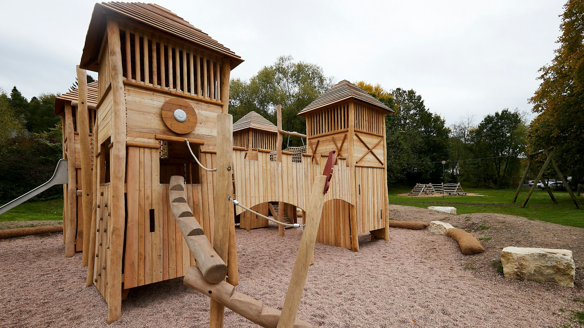 Auf einem Spielplatz steht eine Burg aus Holz.