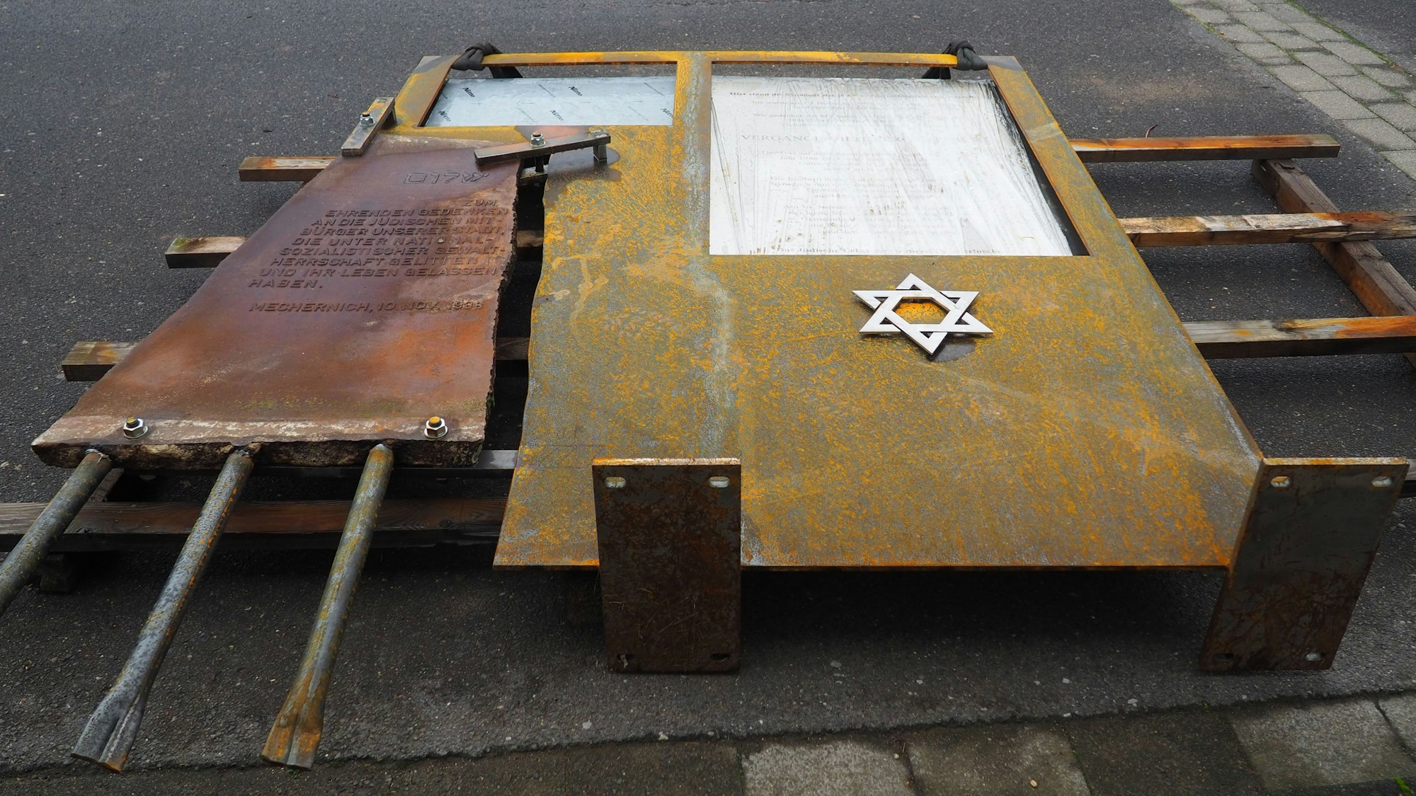 Auf dem Boden liegt eine Stahlplatte, in deren eine Ecke ein Gedenkstein eingesetzt ist.