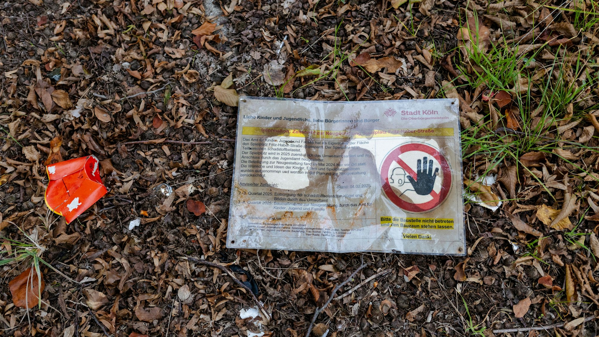 Ein laminiertes Schild liegt auf dem Boden. Auf ihm ist ein Warnhinweis "Betreten verboten" zu lesen.