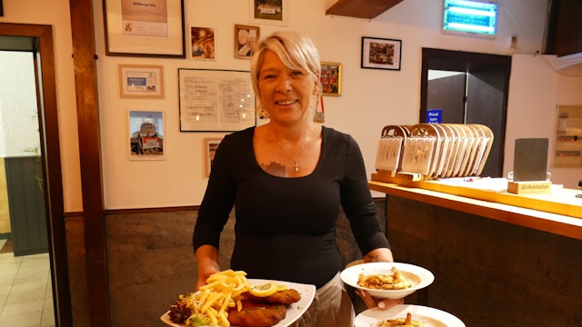 Wirtin Steffi Böckem hält Teller mit deftigem Essen in der Hand.