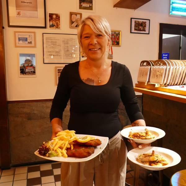 Wirtin Steffi Böckem hält Teller mit deftigem Essen in der Hand.