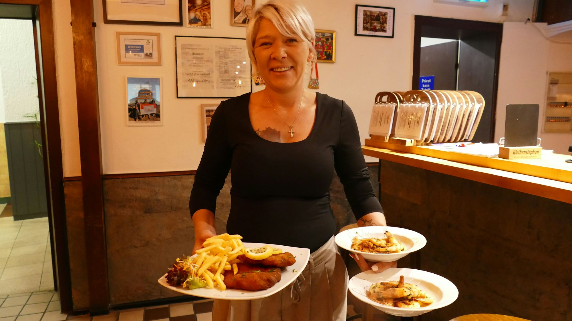 Wirtin Steffi Böckem hält Teller mit deftigem Essen in der Hand.