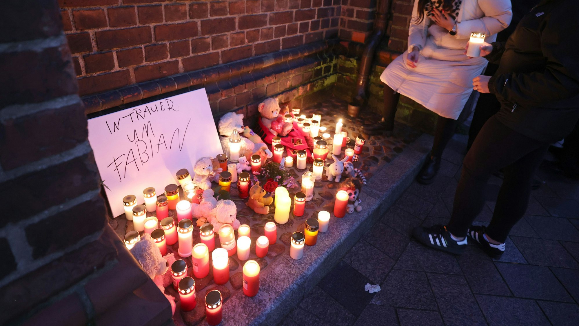 Vor Beginn eines Trauergottesdienstes stellen Teilnehmer Kerzen und Andenken vor die Marienkirche.