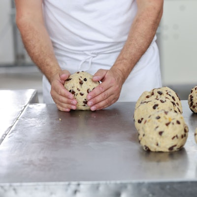 Das Bild zeigt die Hand eines Bäckers, die einen Teigrohling formt.