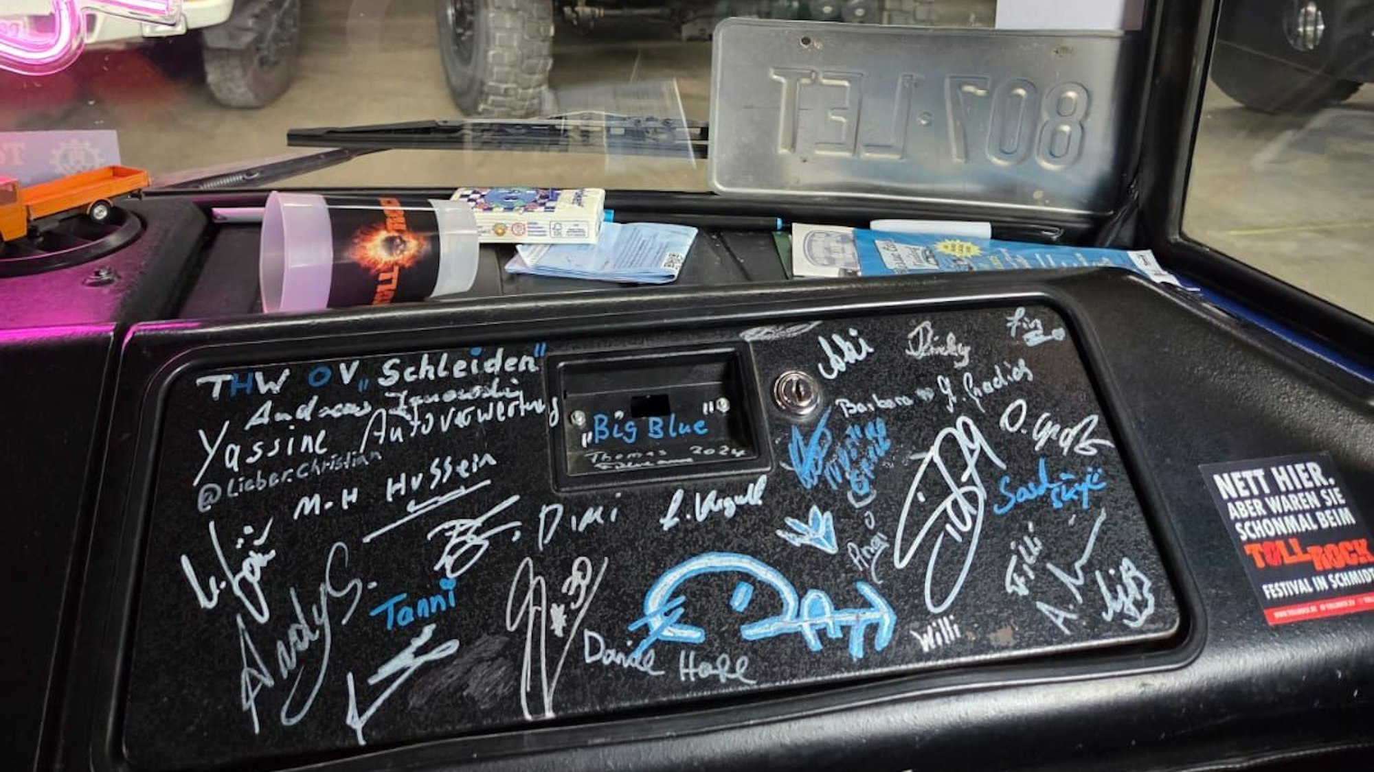 Auf einer schwarzen Kunststoff-Verkleidung im Führerhaus eines Lkw sind zahlreiche Autogramme.