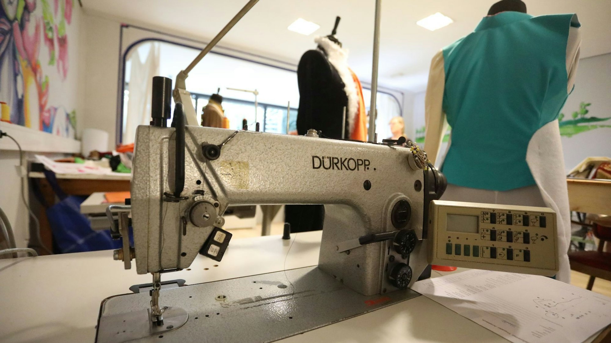 Eine alte Nähmaschine, daneben zwei Kleiderpuppen.