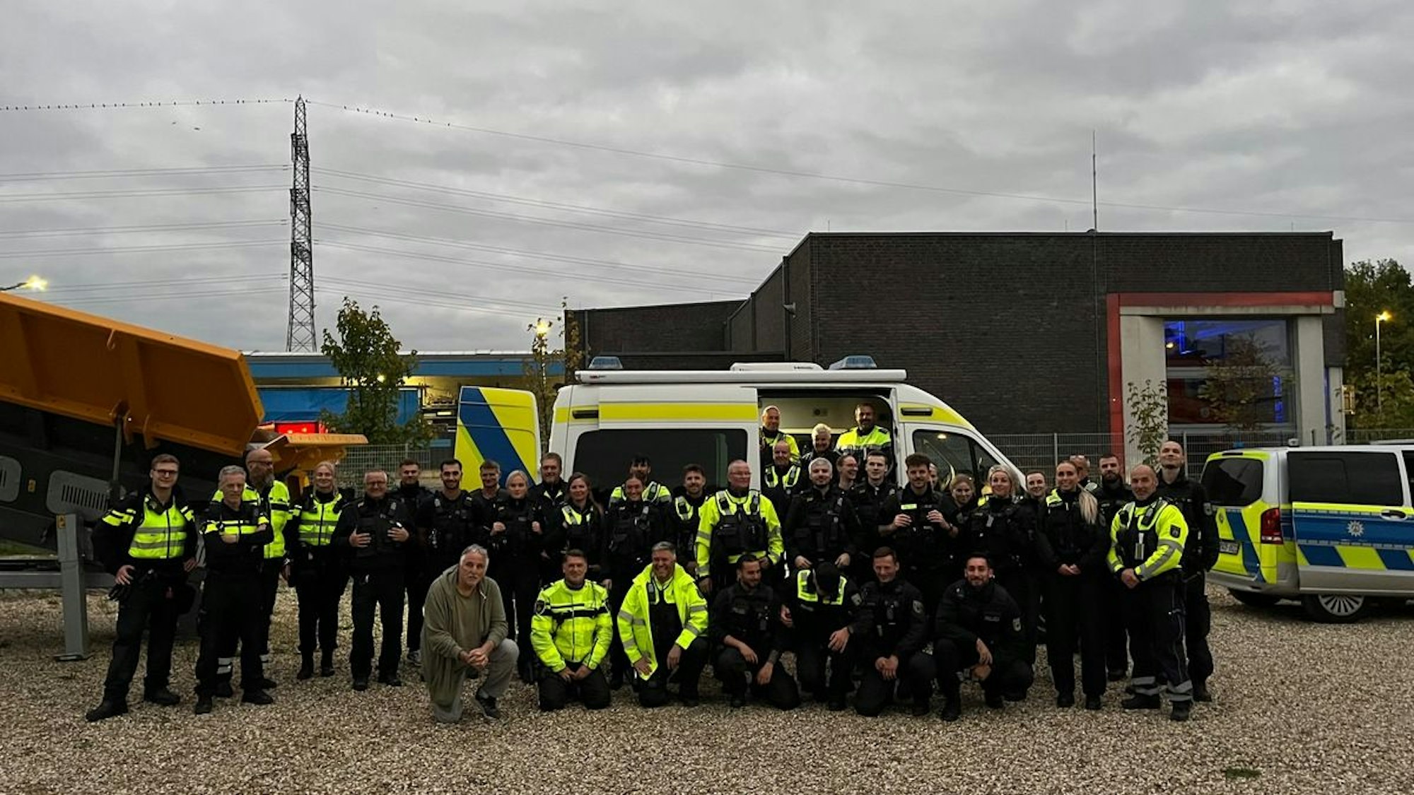 Ein Polizeiauto und mehrere Beamte bei einer nächtlichen Kontrolle auf einer Straße.
