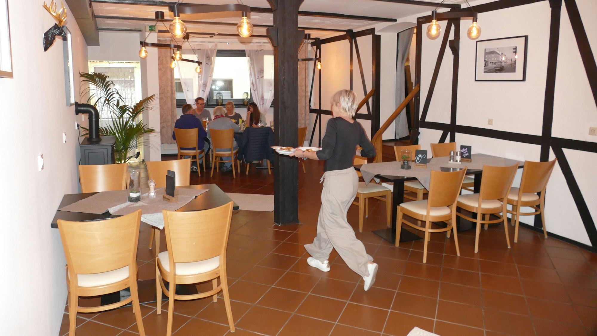 Steffi Böckem bringt Teller mit Essen zu ihren Gästen in der Dorfschänke