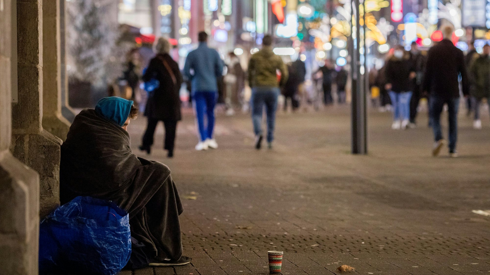 Das Bild zeigt einen in Decken gehüllten Menschen in der Kölner Innenstadt. (Symbolbild)