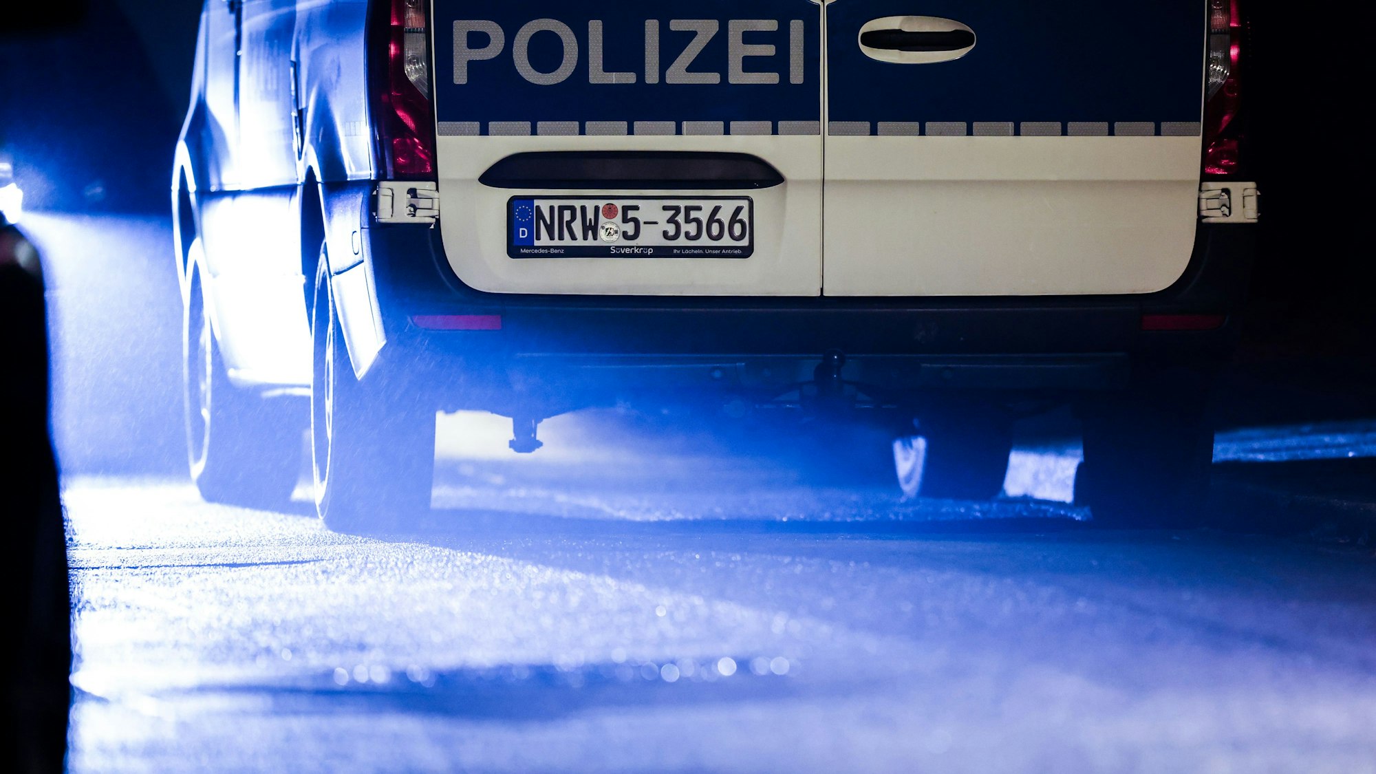 Das Bild zeigt einen Polizeiwagen im Scheinwerferlicht.