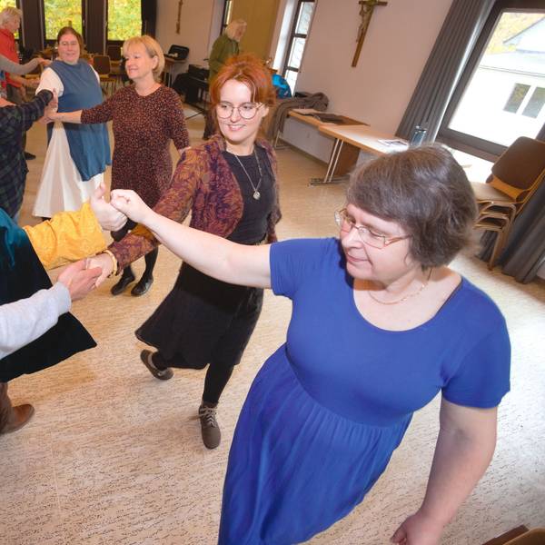 Frauen und Männer üben bei einem Tanzkurs Reigentänze aus vergangener Zeit.